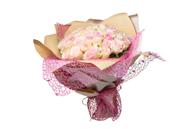 A bouquet of pink and white flowers wrapped in paper with a pink ribbon and decorative netting.